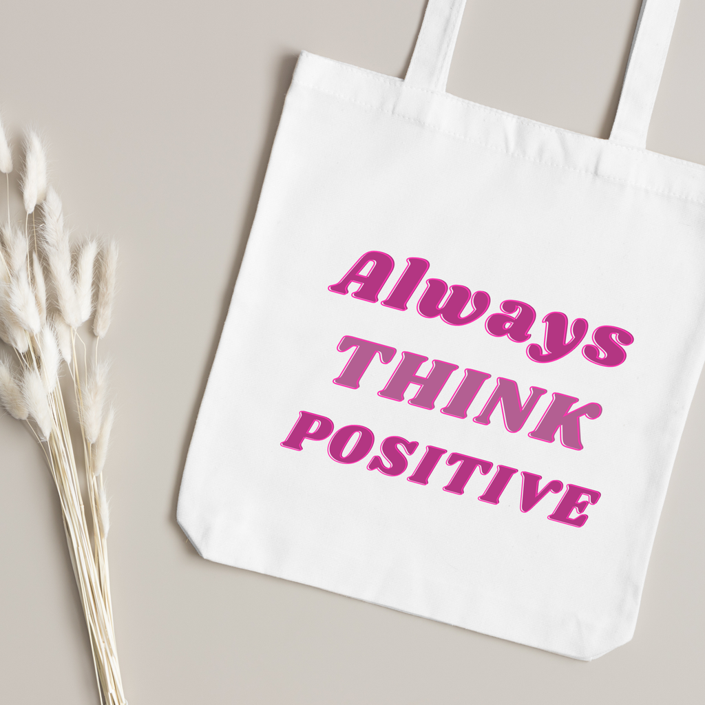 Magenta Always Think Positive lettering close up, dried bunny-tail grass on a taupe surface