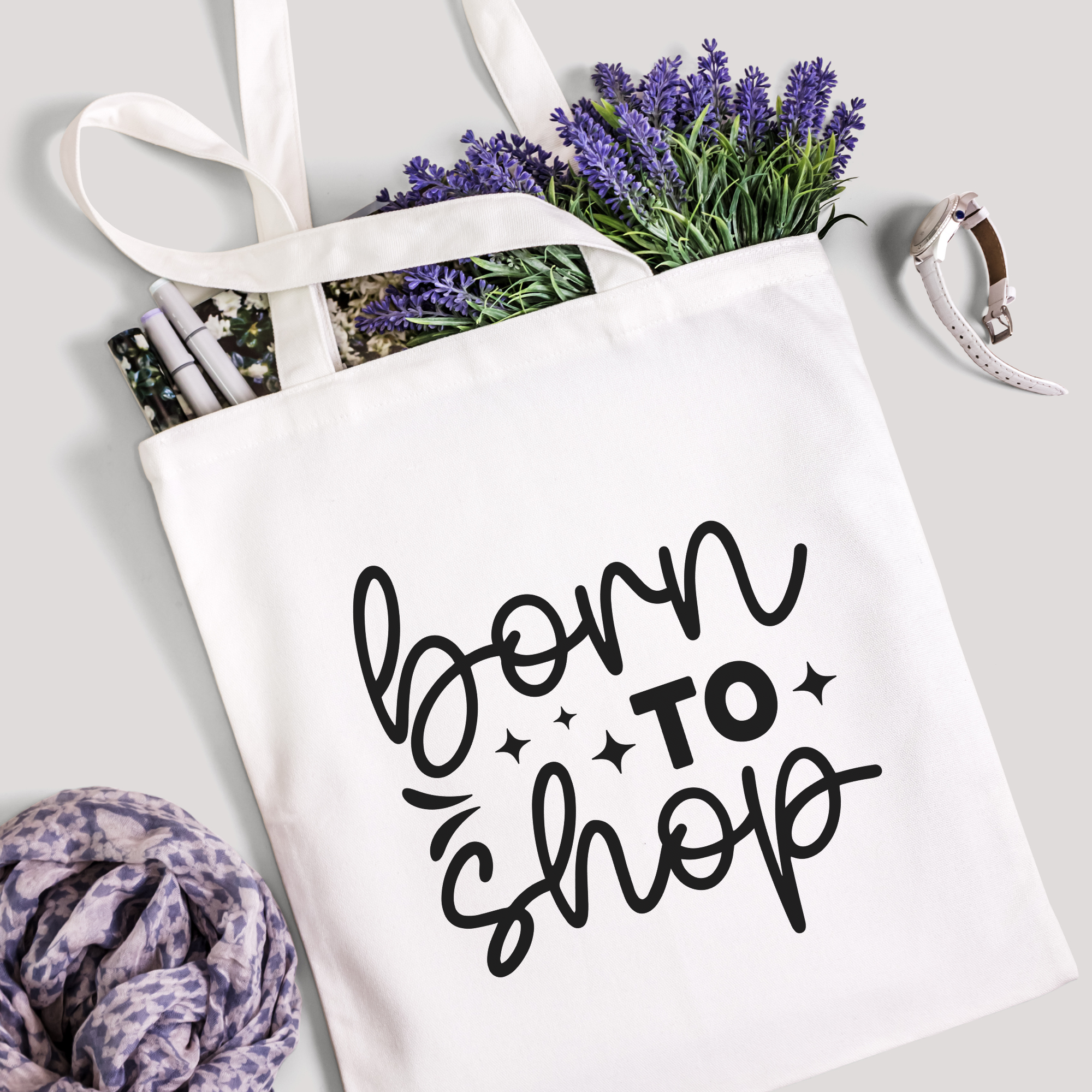 Born To Shop tote filled with lavender stems and marker pens, leopard-print scarf below