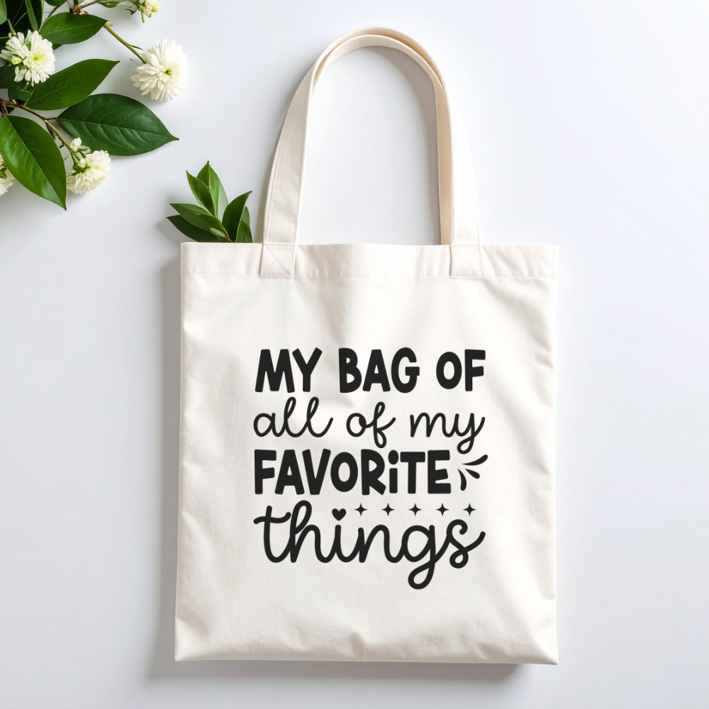 Plovera Co Favorite Things tote laid flat on pale grey with white blossom and green leaves