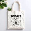 Plovera Co Good Mood tote laid flat on pale grey with white blossom and green leaves