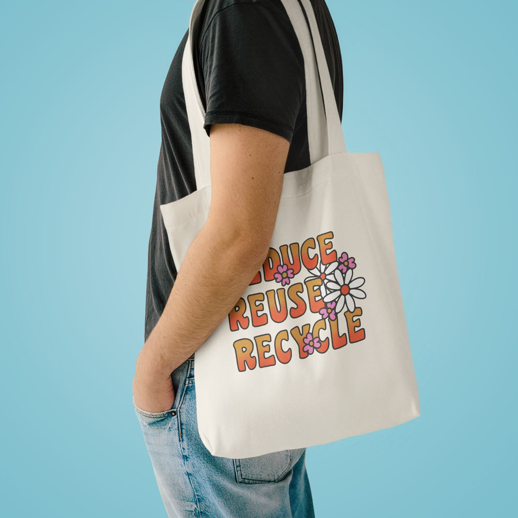 Reduce Reuse Recycle tote over the shoulder of a person in a charcoal tee against pale blue
