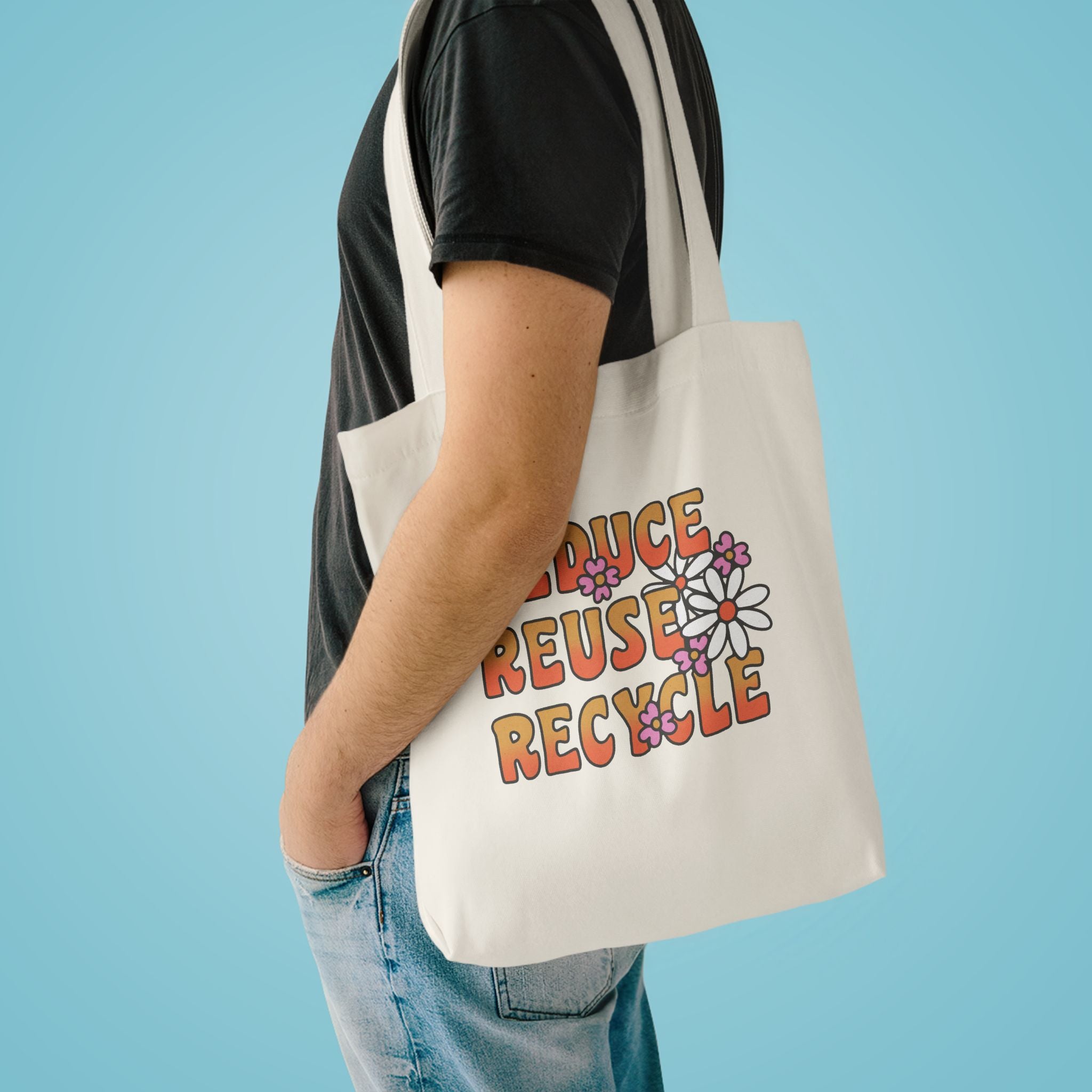 Reduce Reuse Recycle tote over the shoulder of a person in a charcoal tee against pale blue