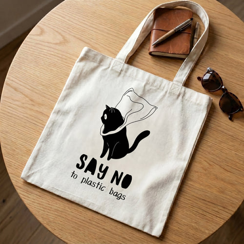 Say No to Plastic Bags tote on a round oak table with a leather notebook, pens and sunglasses
