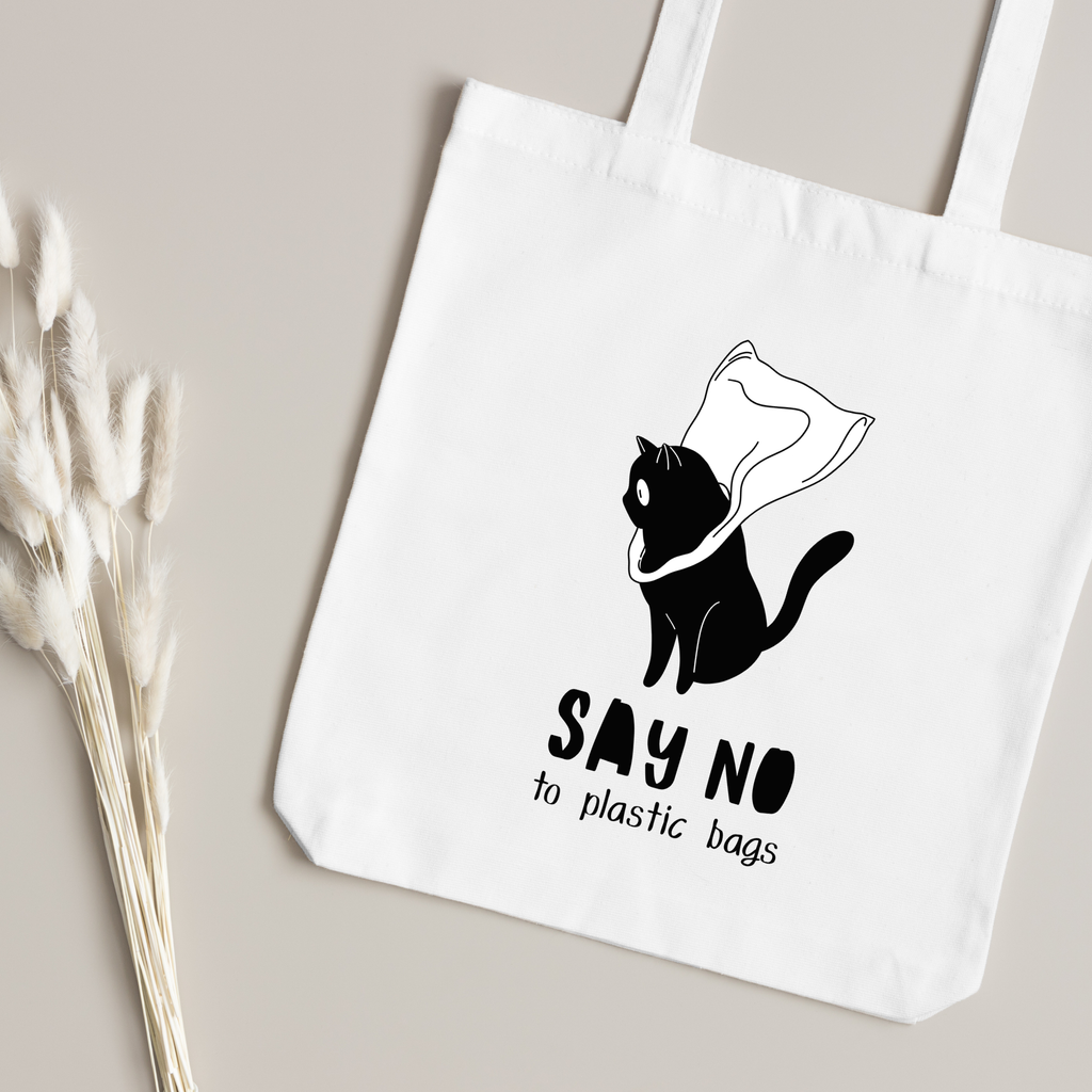 Black cat batting at a plastic bag printed in close up, dried grass on a taupe surface