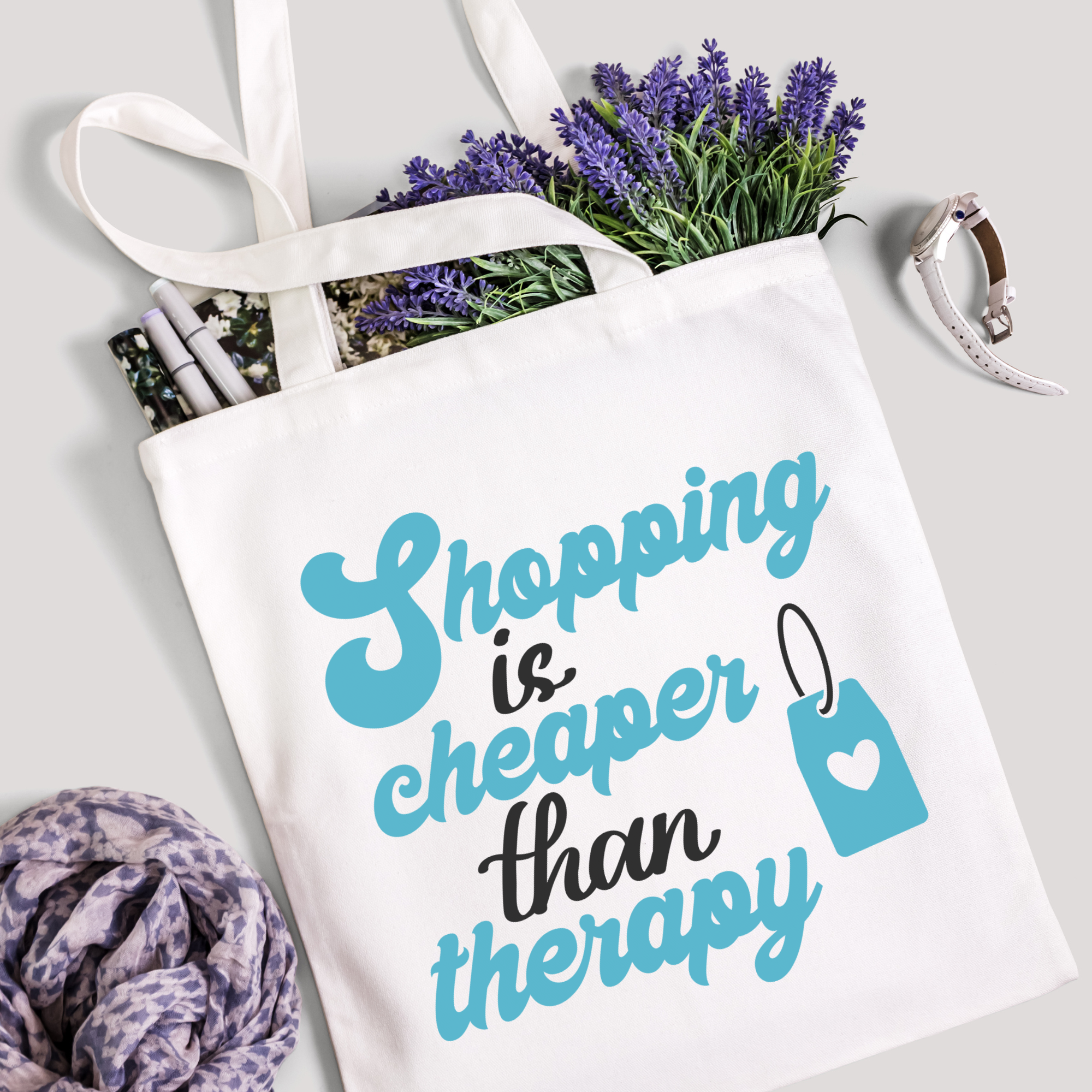 Shopping Is Cheaper Than Therapy tote filled with lavender stems and marker pens, scarf below