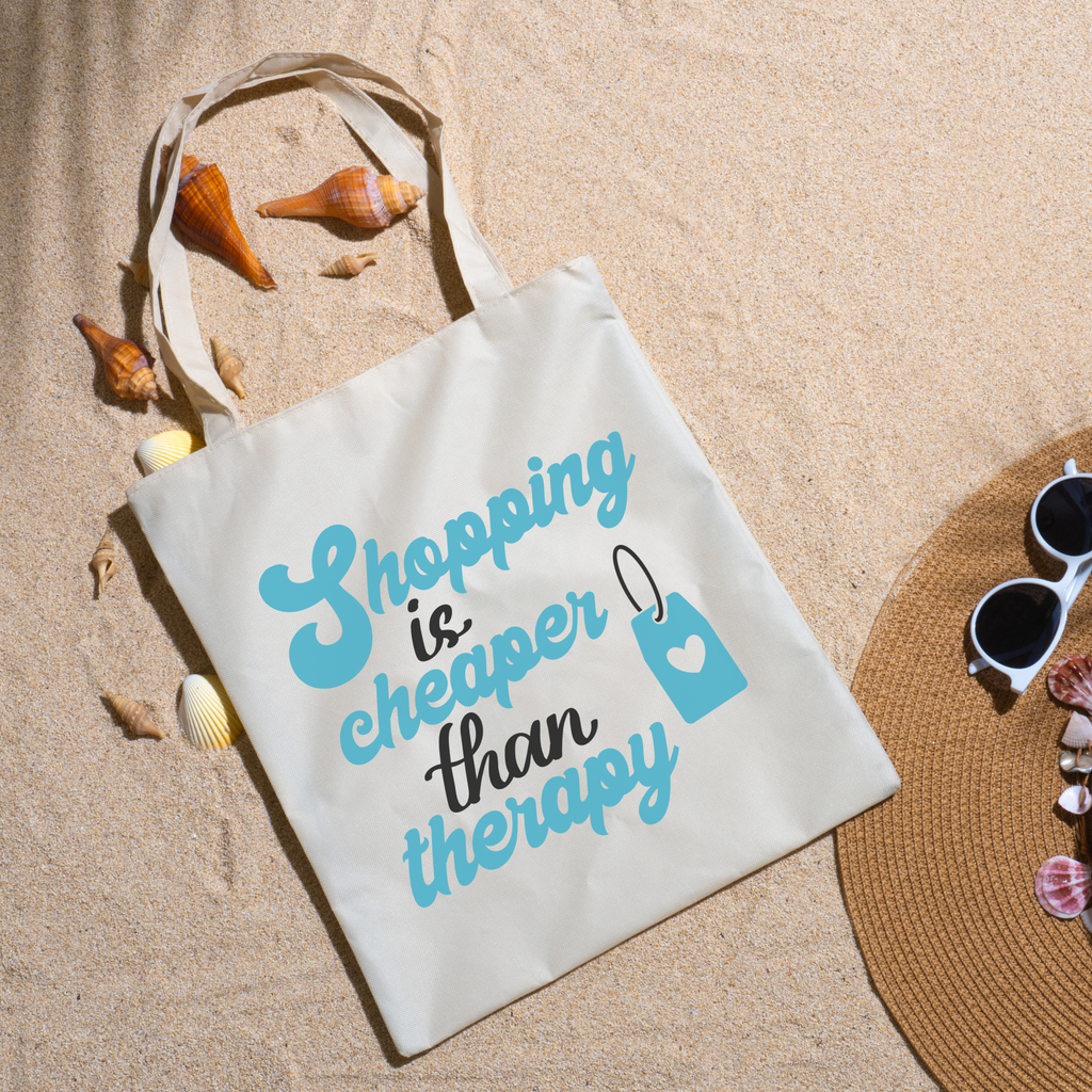 Blue Shopping Is Cheaper Than Therapy lettering on sand with seashells, straw hat and sunglasses