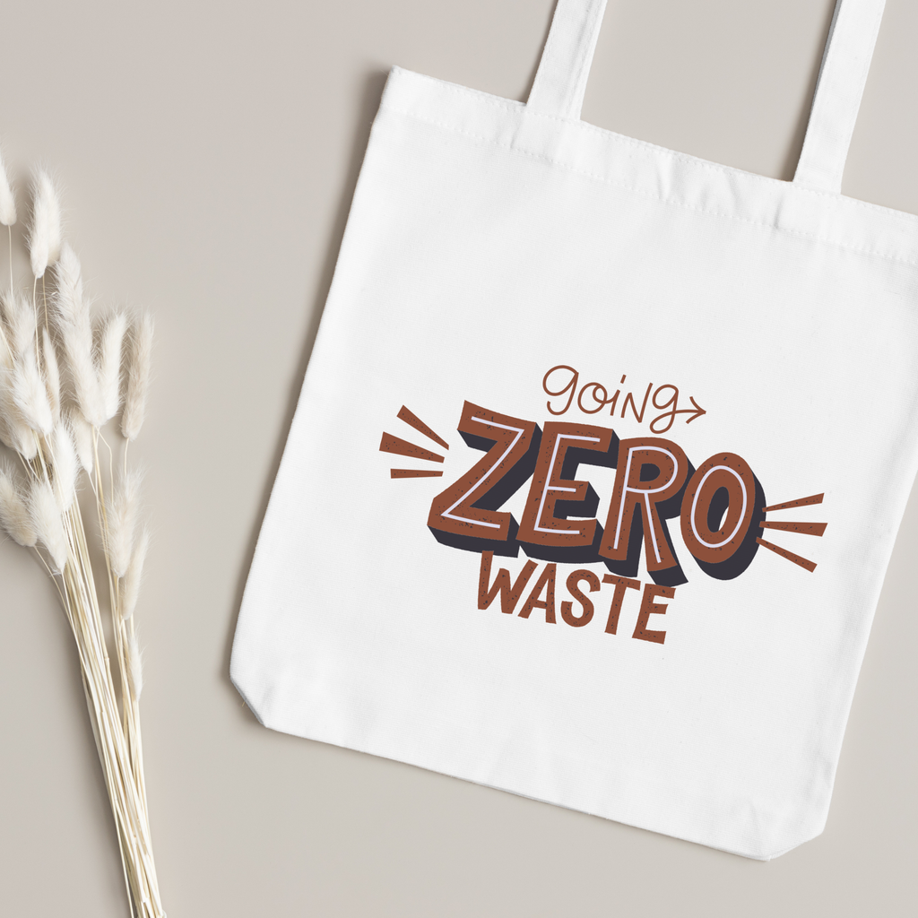 Rust and navy Going Zero Waste lettering close up, dried bunny-tail grass on a taupe surface